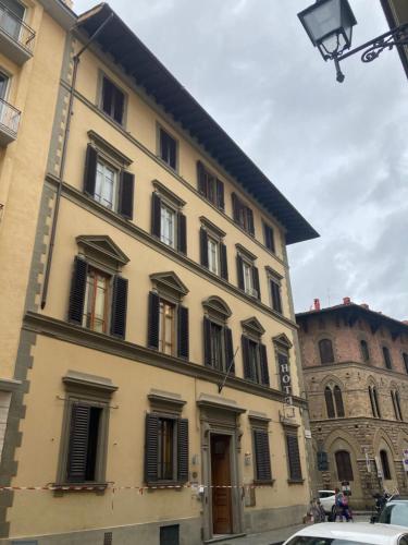 佛罗伦萨Hotel Cimabue的大型黄色建筑,设有黑色百叶窗