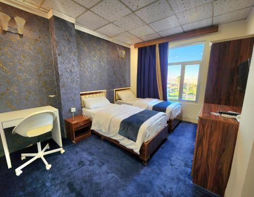 埃尔比勒Vote Hotel的一间卧室设有两张床、一张桌子和一个窗口。