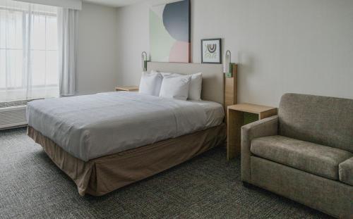 丹佛High Plains Hotel at Denver International Airport的配有一张床和一把椅子的酒店客房