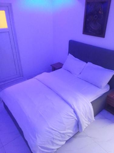 拉各斯Ge-Mart Hotels and Suites的卧室配有一张带白色床单和枕头的大床。