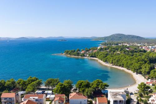 皮罗瓦茨Apartments with a parking space Pirovac, Sibenik - 17653的享有树木和房屋的海滩美景