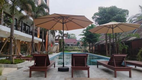 万荣Vang Vieng Bungalows的度假村前方的带椅子和遮阳伞的游泳池