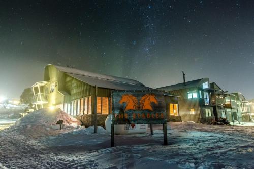 佩里舍峡谷Studio 2 - The Stables Perisher的一座在夜间有雪标的建筑