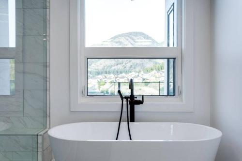 基洛纳Luxury Golf Stay w/Hot Tub的带窗户的浴室内的白色浴缸