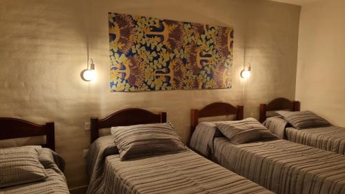 多洛雷斯镇Hotel Hualum的一间设有三张床的客房,墙上挂着一幅画
