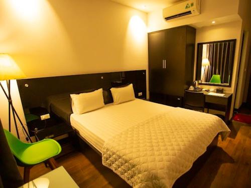 河内Ánh Hồng Hottel的酒店客房,配有一张床和一把绿色椅子