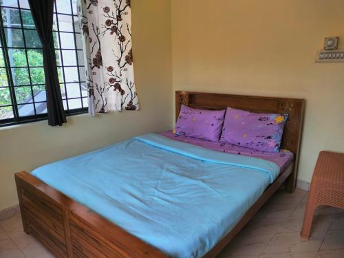 马迪凯里White bungalow的一间卧室配有一张带紫色床单和窗户的床。