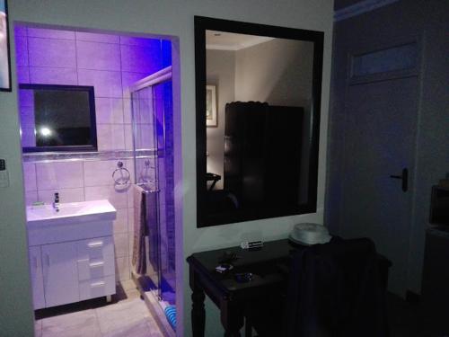 韦尔科姆Victoria Mea Est的浴室配有水槽和带紫色灯的淋浴