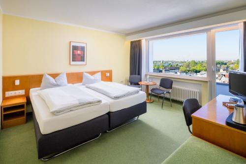 克雷费尔德克雷菲尔德花园酒店的配有一张床、一张书桌和一扇窗户的酒店客房