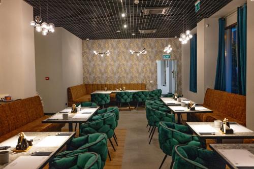 蒂米什瓦拉Opera Hotel的用餐室配有桌子和绿色椅子