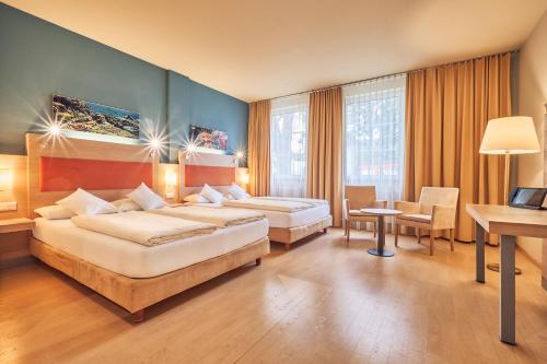阿夫吉岑AKZENT Hotel Aufkirchen的酒店客房配有两张床和一张书桌