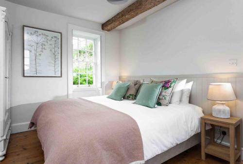 斯特劳德A beautiful Cotswolds Cottage in Stroud的白色卧室配有一张带绿色枕头的大床