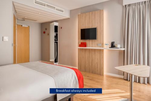 梅赫伦梅赫伦市中心快捷假日酒店的一间卧室配有一张床、一台电视和一张桌子