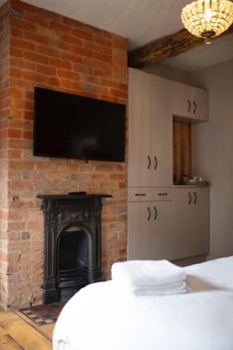 奥尔顿Bulls Head Inn Rooms的卧室设有壁炉,砖墙上配有电视