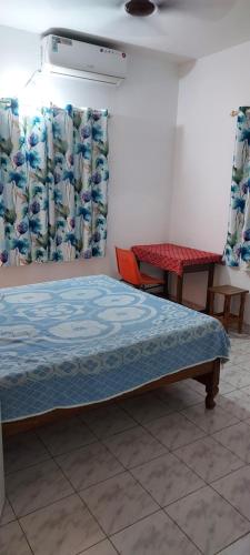 班加罗尔RUKMINI Apartment的配有窗帘和桌子的房间的一张床位