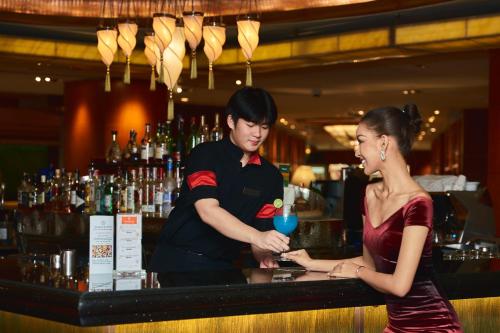 曼谷Royal Orchid Sheraton Hotel and Towers的站在酒吧的男人和女人