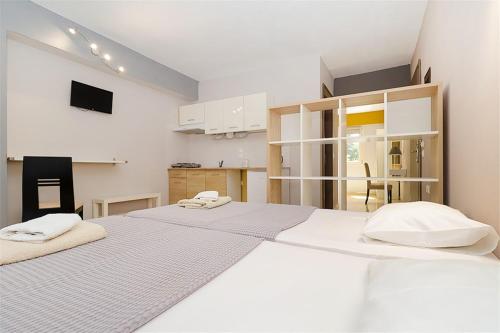 卡利塞亚-豪客迪克斯ER.ZO Summer Studios的配有白色墙壁和白色橱柜的客房内的两张床