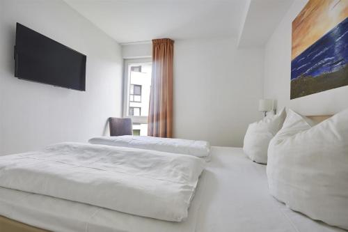 巴贝Strandvilla Baabe 20 ABENDROT的一间白色卧室,配有两张床和一台平面电视