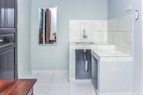 古邦Amor Homestay near Eltari International Airport Mitra RedDoorz的白色的厨房配有水槽和镜子