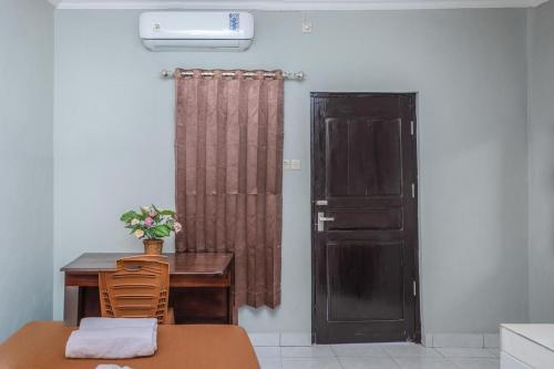 古邦Amor Homestay near Eltari International Airport Mitra RedDoorz的客房设有书桌、门、桌子和椅子。