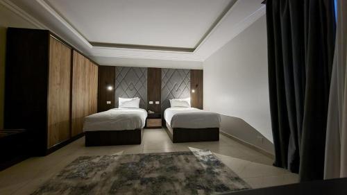Qaryat ash ShamālīGrand Plaza 6 Octobar的酒店客房带两张床和地毯