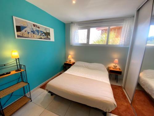 热拉梅Aux pieds des pistes 4/6 personnes的一间卧室设有蓝色的墙壁和一张带两盏灯的床。