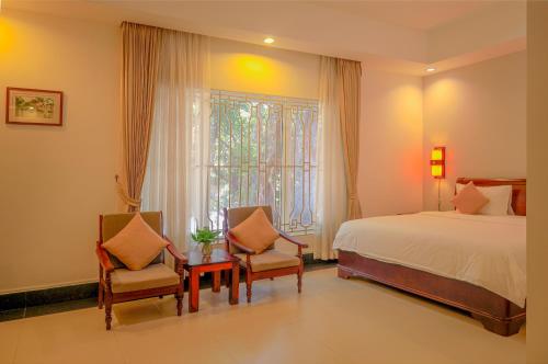 金边Skyline Boutique Hotel Phnom Penh的一间卧室配有一张床、两把椅子和一个窗户
