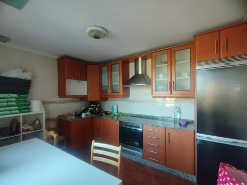 拉科鲁尼亚Alojamiento PLAYA DE PANTIN的厨房配有木制橱柜和不锈钢冰箱。