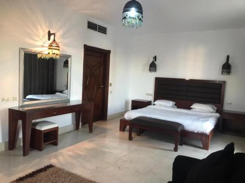沙姆沙伊赫samara villas luxury的一间卧室配有一张床、一张书桌和一面镜子