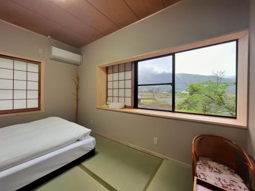 由布市湯布院我楽珍民泊Yufuin Garakuchin的一间卧室设有一张床和两个美景窗户。