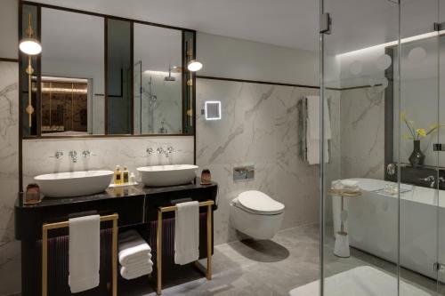 伦敦The Biltmore Mayfair的浴室配有2个盥洗盆、卫生间和浴缸。