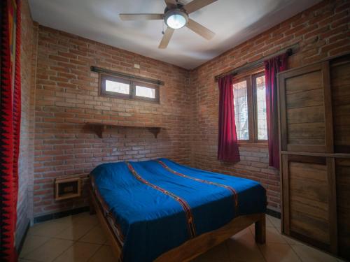 南圣胡安2 bedroom apartment with bay view, deck and roof terrace的一间卧室设有蓝色的床和砖墙