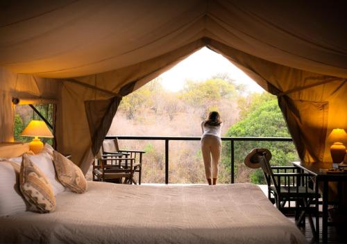 OlolaimutiekSekenani Camp Maasai Mara的站在帐篷阳台的女人