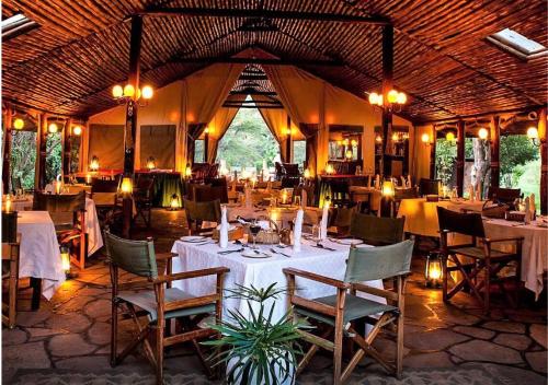 OlolaimutiekSekenani Camp Maasai Mara的帐篷内带桌椅的用餐室