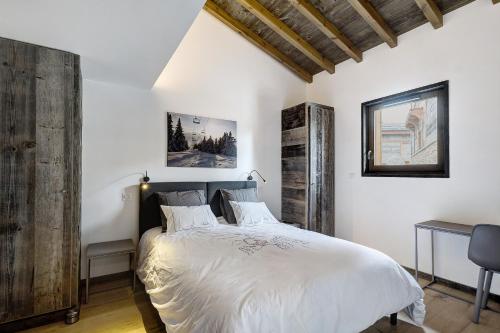 丰罗默奥代洛维亚Chalet nid des écureuils的一间卧室配有一张带白色床单和木墙的床。