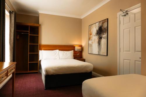 都柏林凤凰公园酒店的一间酒店客房,设有两张床和一扇门