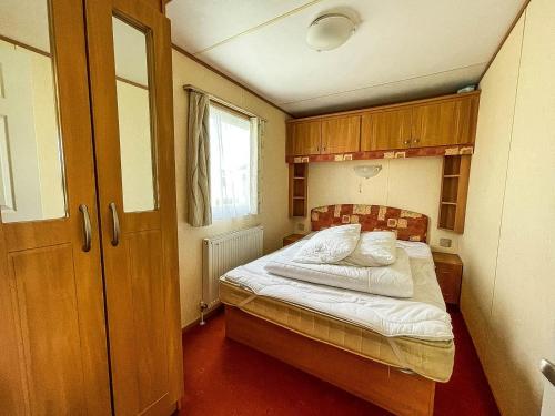 赫彻姆8 Berth Caravan For Hire At Heacham Holiday Park In Norfolk Ref 21024f的一间小卧室,配有白色床单