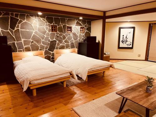 由布市Yufuin Tsukawara Kogen Sanctuary - Vacation STAY 91378v的一间卧室设有两张床和石墙