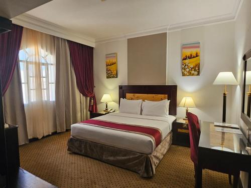 马斯喀特Caesar Hotel的配有一张床和一张书桌的酒店客房