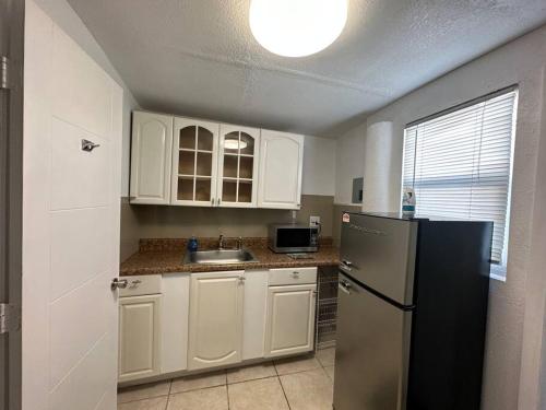迈阿密花园Miami Breeze Studio的厨房配有白色橱柜和黑色冰箱。