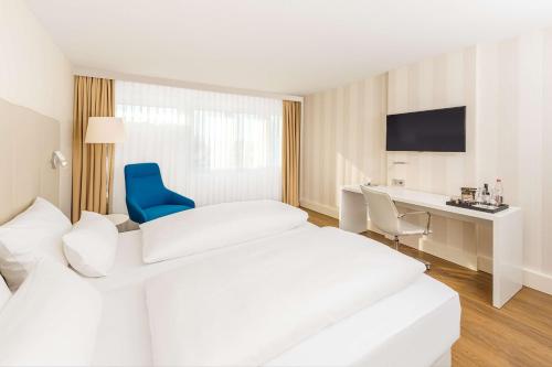 埃朗根埃朗根NH酒店的酒店客房,设有两张床和一张蓝色椅子