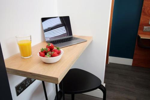卡迪夫Boutique one bedroom apartment in Cardiff的一张桌子,上面放着一碗草莓和一杯橙汁