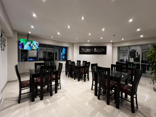 塔克纳Hotel Reggia的餐厅设有黑色桌椅和电视。