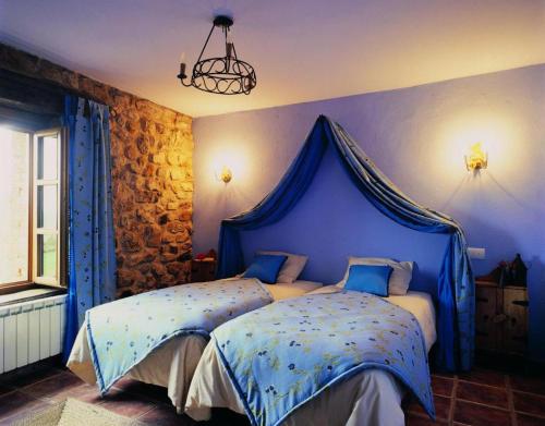 Robledo de la GuzpeñaLa Venta Del Alma的一间卧室配有一张蓝色天蓬床