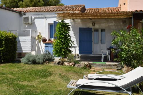 奥尔比亚Sa Domitta di Suiles的白色的小房子,设有蓝色的门和椅子