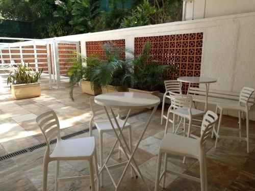 里约热内卢Apartamento Parque Jardim Europa的庭院设有桌子和白色椅子,种有植物