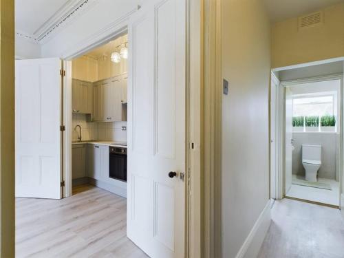 伦敦Pass the Keys Modern Apartment in East London的开放式厨房配有白色橱柜和卫生间。