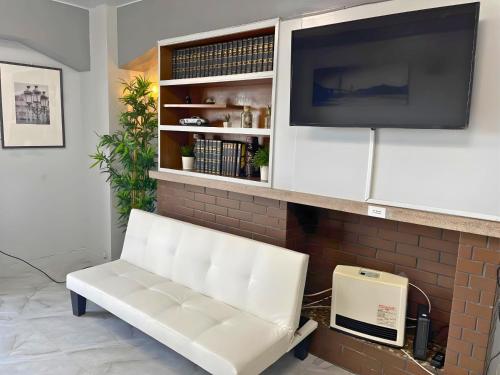 神户Sea View Court Kobe的带电视的客厅的白色长凳