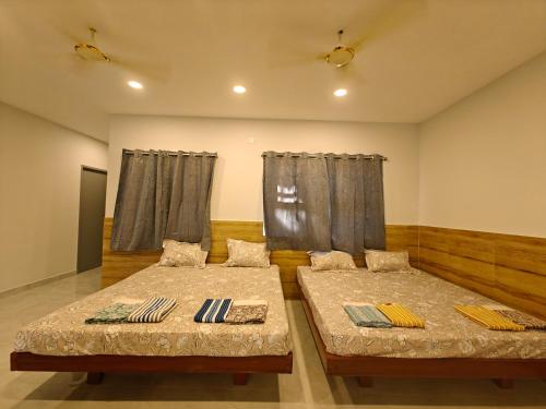 钦奈HOMESTAY - AC 5 BHK NEAR AlRPORT的两张床铺,位于带窗帘的房间