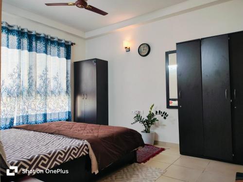 班加罗尔SOLACE Premium 3BHK Apartment Manyata Tech Park and Mall of Asia的卧室配有一张床,墙上挂着一个钟